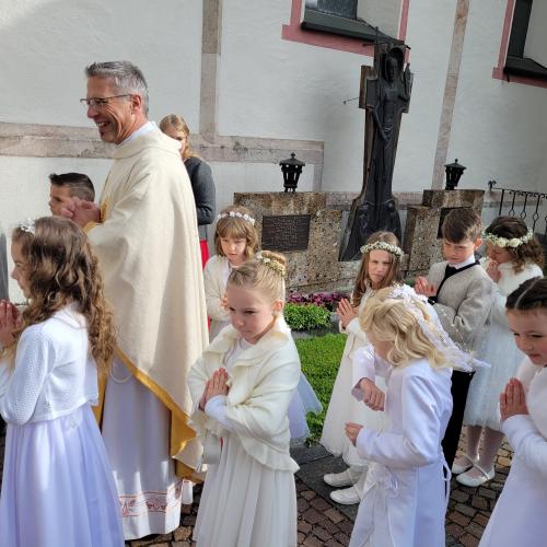 Pfarrer wartet mit Kindern vor der Kirche