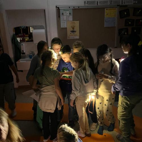 Kinder lösen Rätsel im Dunklen mit Taschenlampen