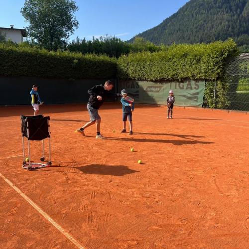 Kinder üben auf dem Tennisplatz
