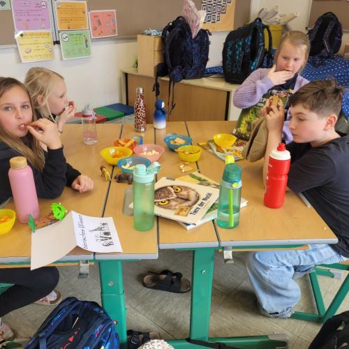 Kinder lesen an verschiedenen Plätzen in der Klasse und knabbern Snacks 3