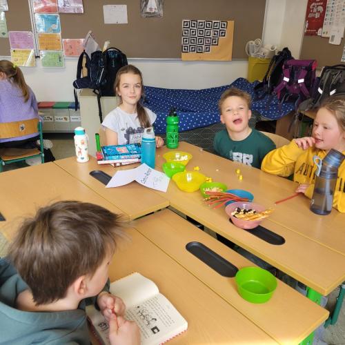 Kinder lesen an verschiedenen Plätzen in der Klasse und knabbern Snacks 1