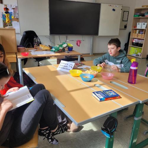 Kinder lesen an verschiedenen Plätzen in der Klasse und knabbern Snacks 2