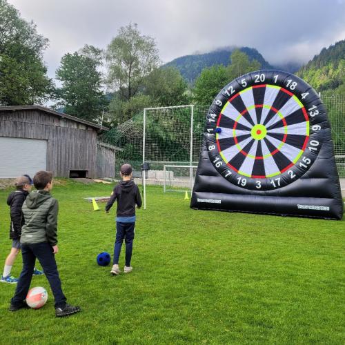 Kinder schießen auf große Dartscheibe mit Fußball