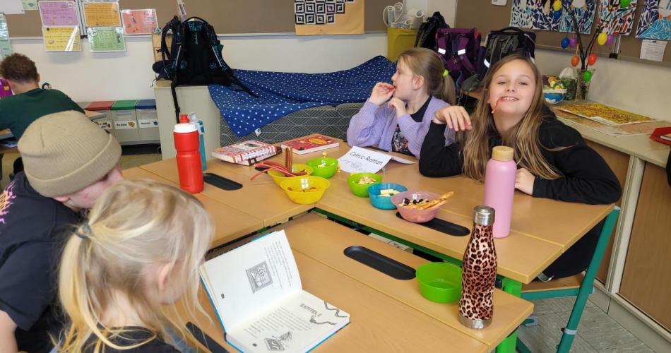 Kinder lesen an verschiedenen Plätzen in der Klasse und knabbern Snacks